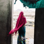 Uma jovem com um vestido rosa e verde nos escombros